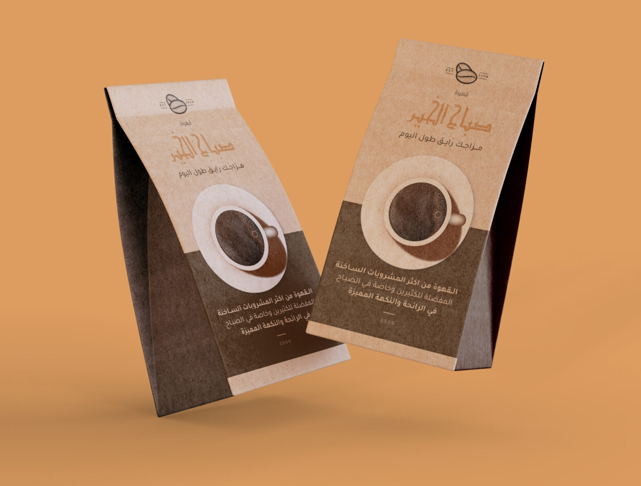 Two coffee bags with Arabic text and a cup of coffee graphic displayed against a warm beige background.