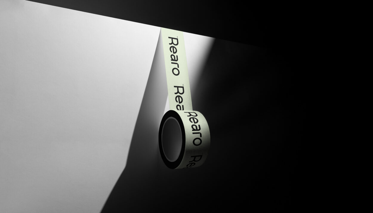 Close-up of hands applying branded packing tape to a shipping box, ensuring secure closure.