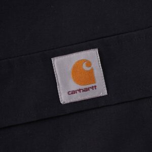 Close-up of a Carhartt logo patch with the brand's signature yellow "C" emblem stitched onto a black fabric background.